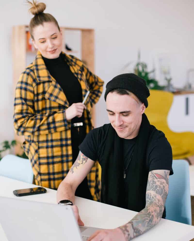 Frau schaut zu, während Mann an einem Laptop arbeitet