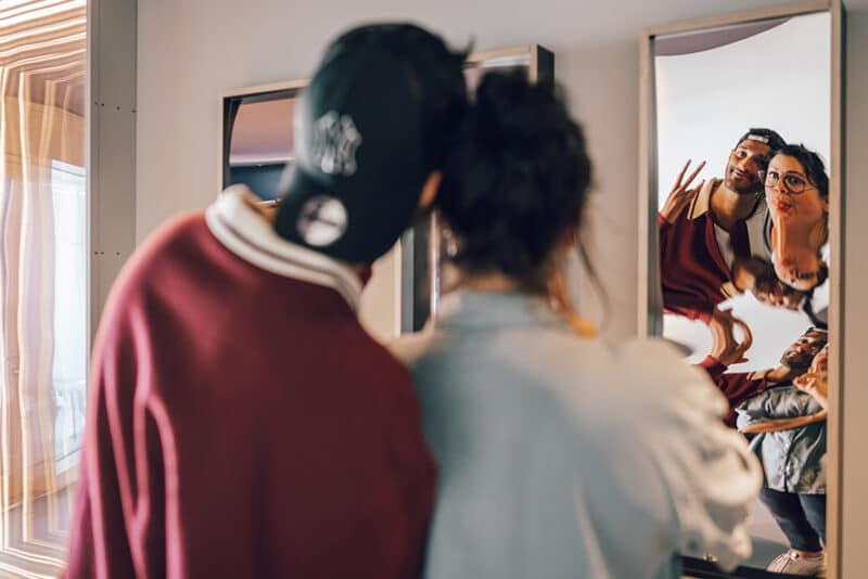 Foto von einem Pärchen, dass vor einem Spiegel im Illusion Space Spaß hat